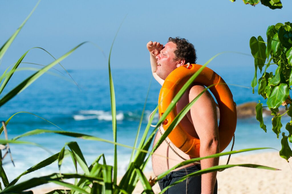 A man with a lifebuoy enjoys a sunny day at the beautiful tropical beach of Unawatuna, Sri Lanka.
